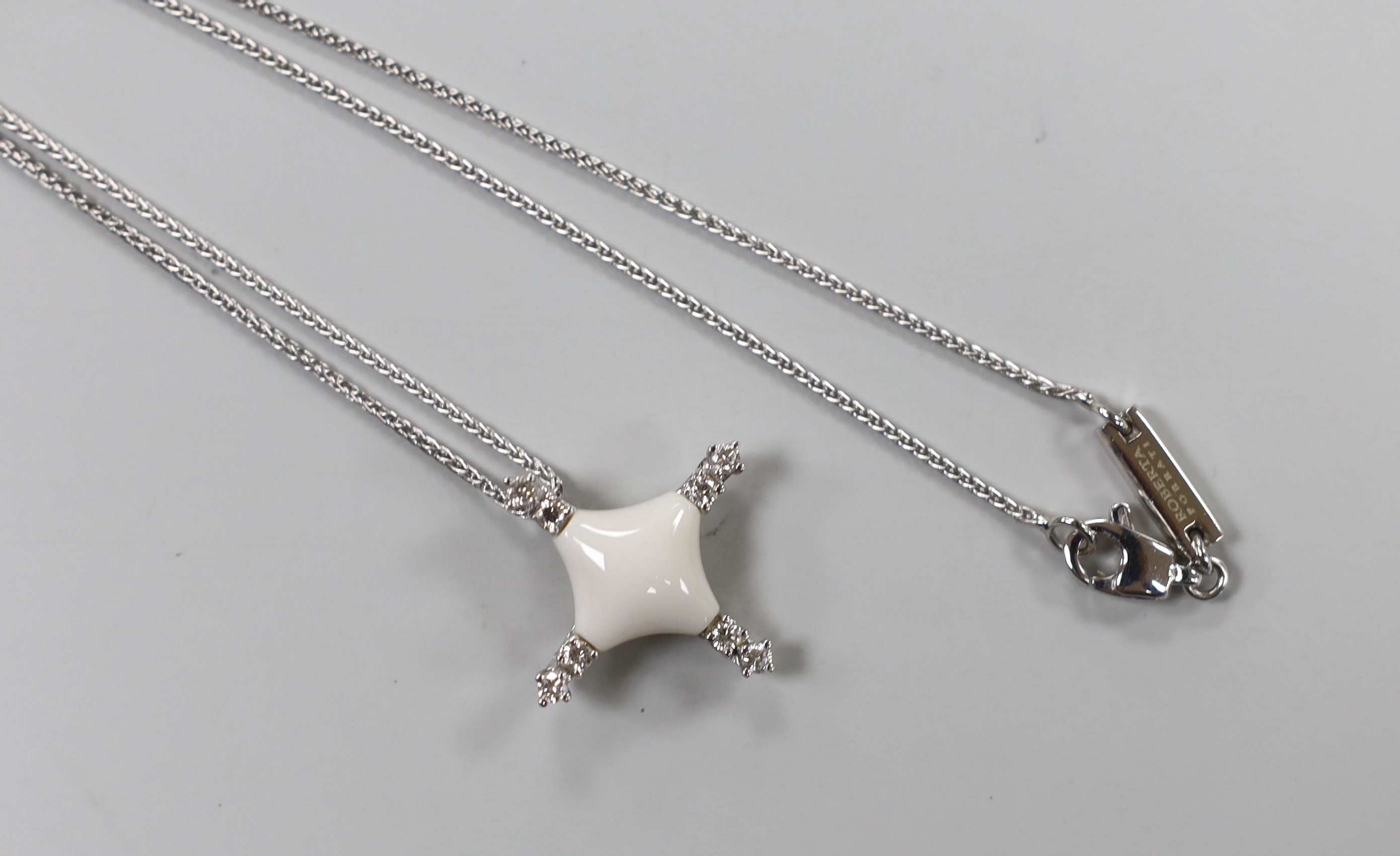 A modern Italian Roberta Porratti 18k white metal, six stone diamond and ceramic? set quatrefoil pendant, 23mm, on an 18k white meal chain, 40cm, signed, gross weight 7.5 grams.